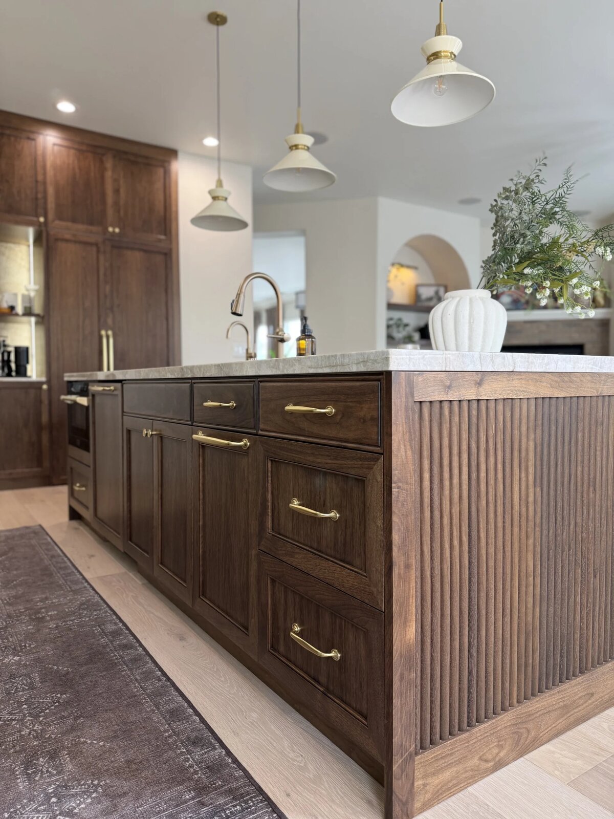 Custom walnut kitchen island with fluted detailing, brass hardware, and quartzite countertop in a Sacramento home remodel