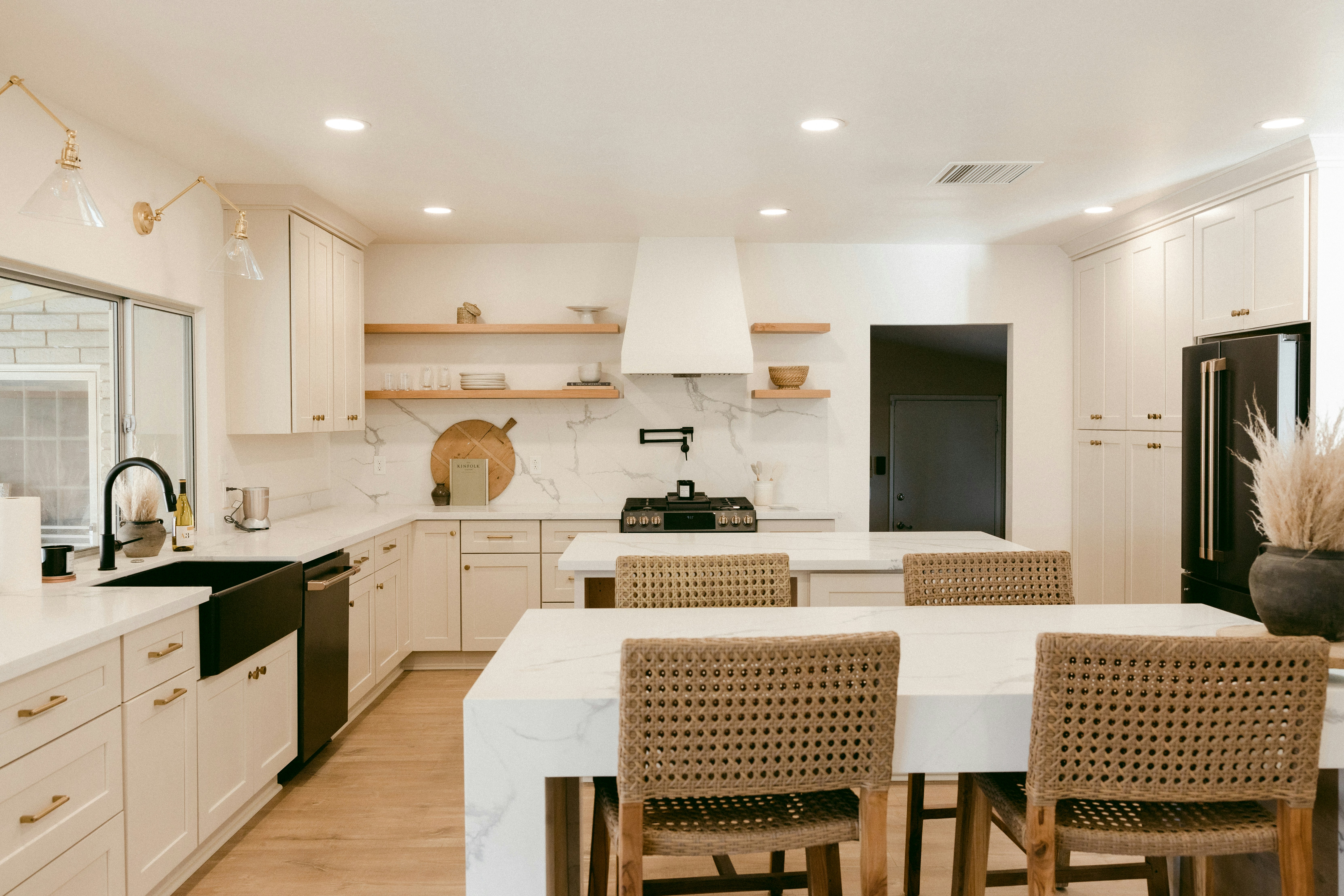 Custom white shaker kitchen with marble island, gold hardware, and rattan bar stools