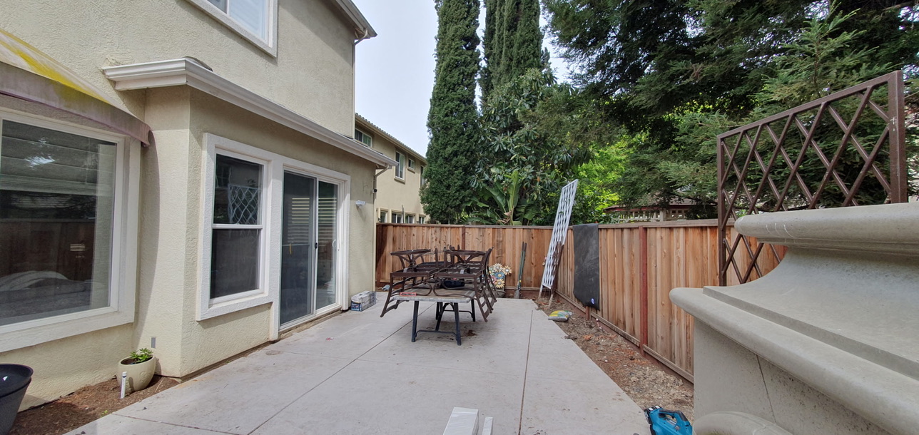 Fresh concrete patio pad ready for outdoor living build-out with privacy fence and mature landscaping
