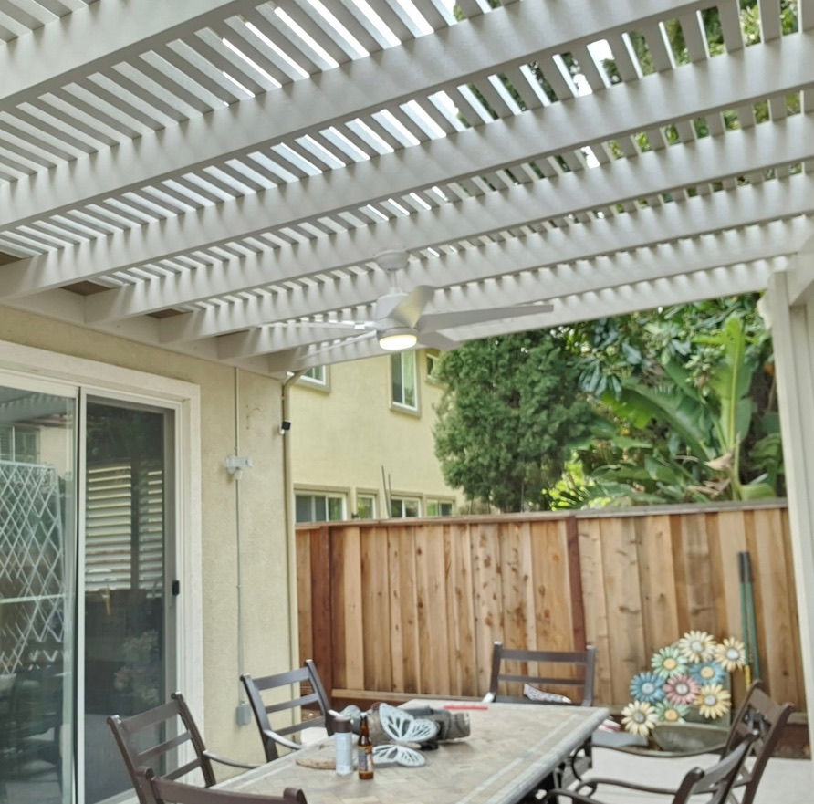 Custom patio cover interior view with louvered roof slats and integrated ceiling fan