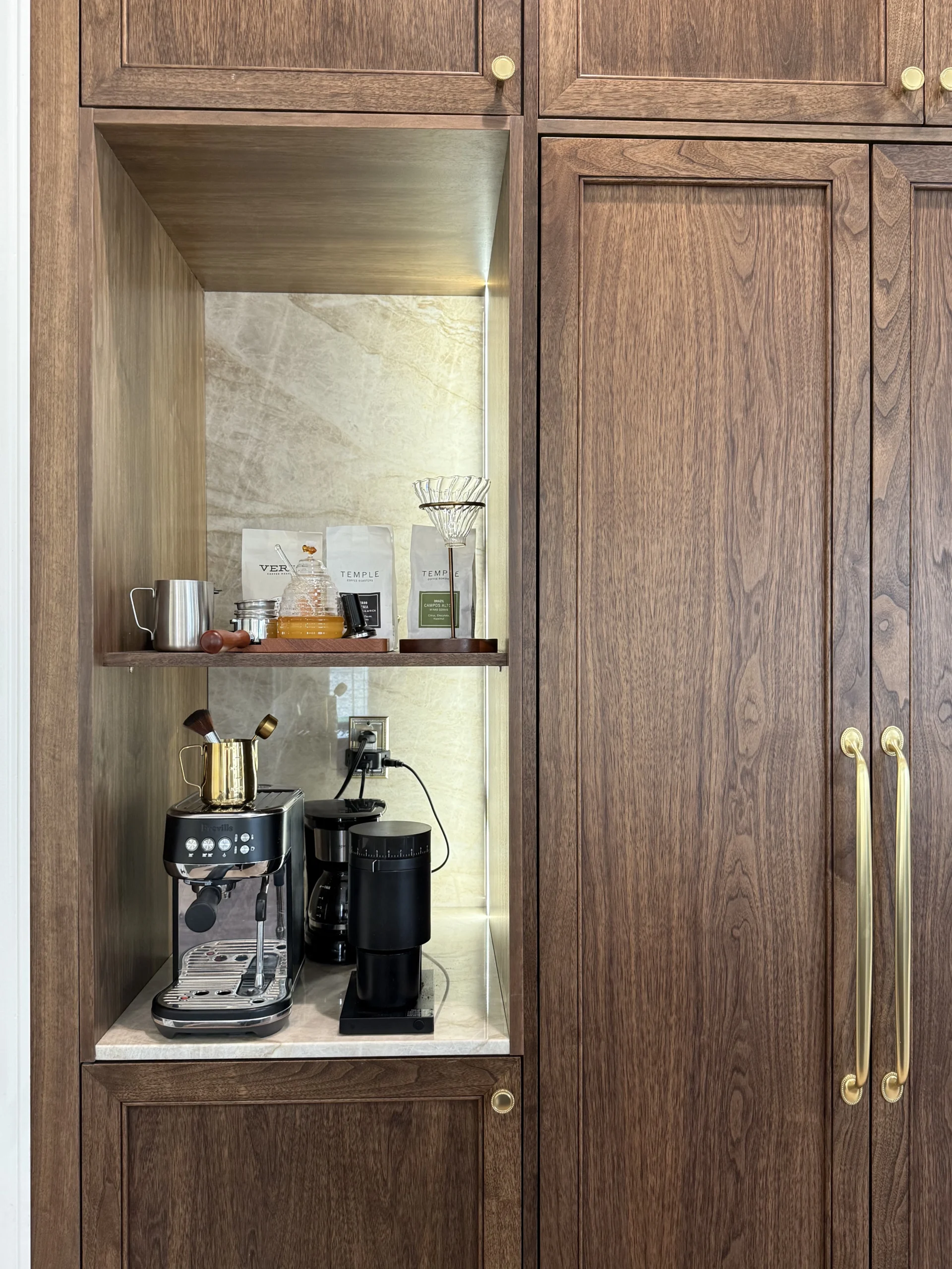 Built-in walnut pantry with integrated coffee bar niche, marble back panel, and brass cabinet pulls